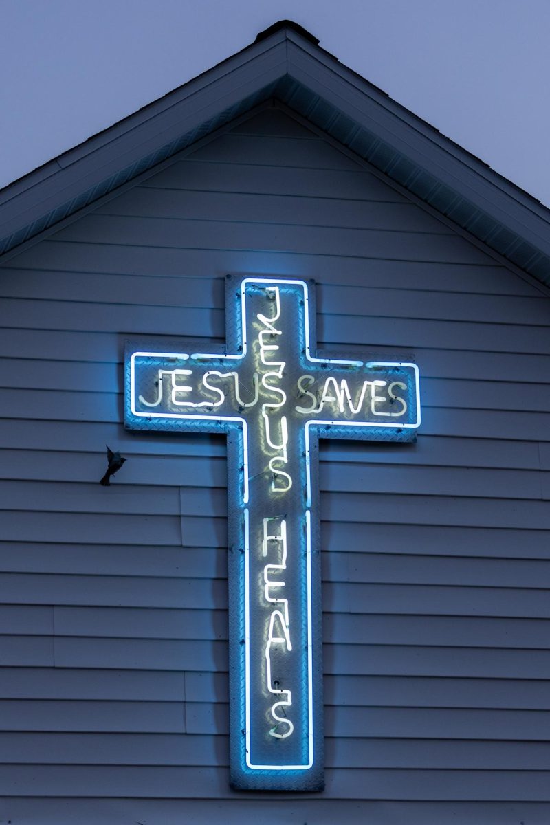 At dawn, a bird flys up to land on the neon cross sign displayed over the front door of Full Gospel Pentecostal Church April 13, 2024 in Alto Pass, Illinois. 
