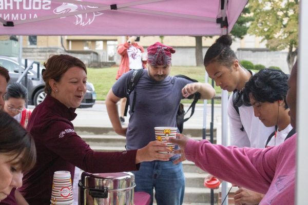 Michelle Dirks hands out coffee in the morning to students who came to the Paws for 5 giveaway of coffee and donuts Sept. 3, 2024 outside of the Alumni
Center in Carbondale, Illinois. @enanchediakphotography