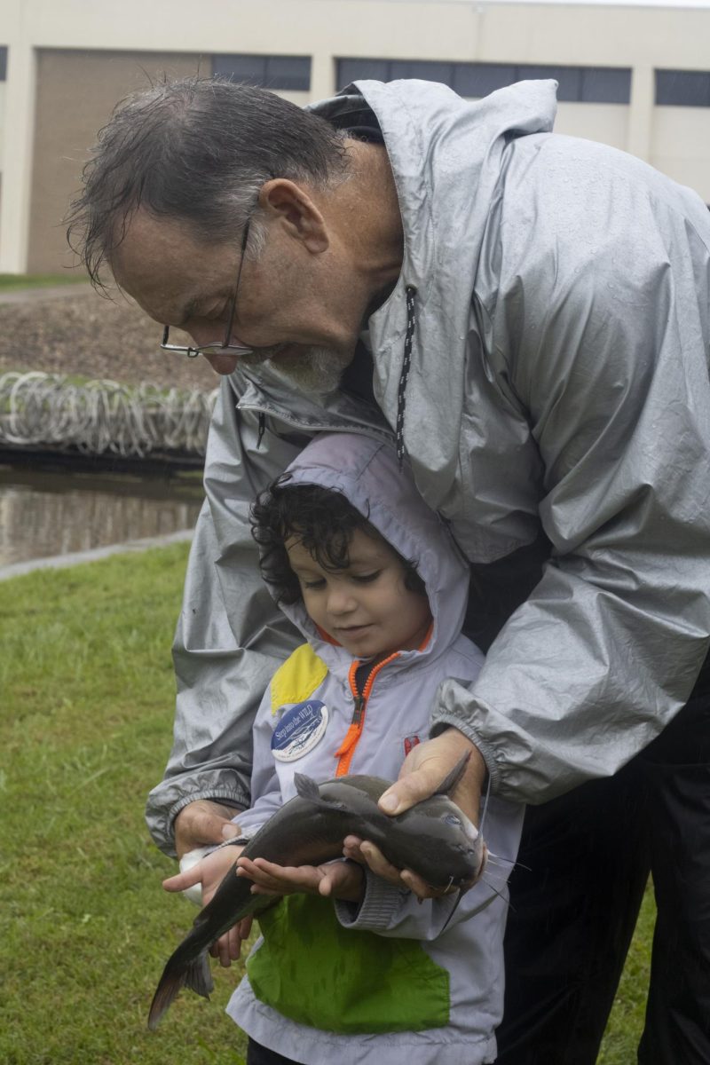 Rick Wright shows his grandson King Mason how to hold the channel catfish that he caught in the pond at John A. Logan for a portrait Sept. 28, 2024 at Hunting and Fishing Days in Carterville, Illinois. 
