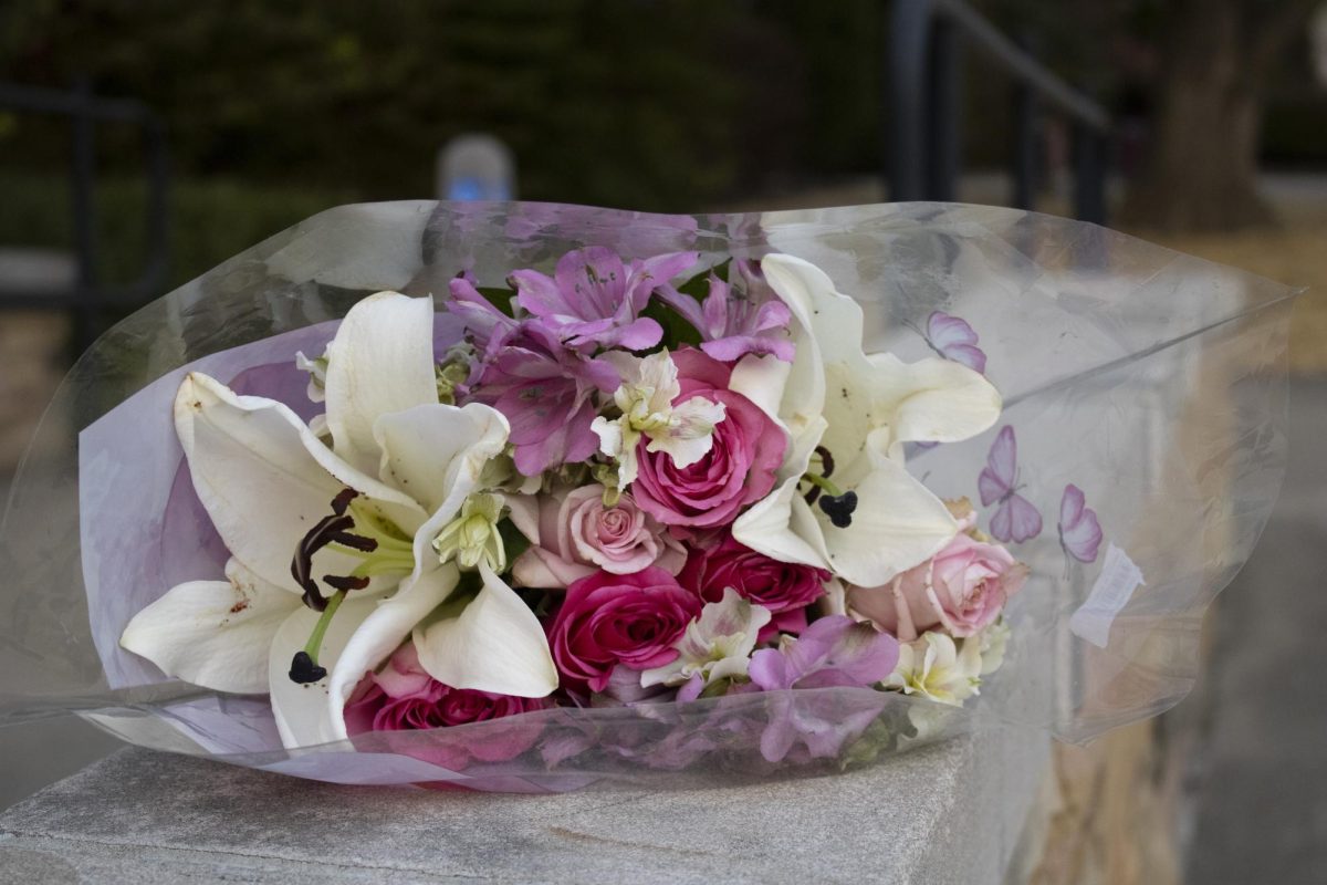 Flowers brought by Taylor Hughes sit on a embankment wall before the vigil for Lyric Irby Oct. 22, 2024 on the steps of the Parkinson Building at SIU in Carbondale, Illinois.  
