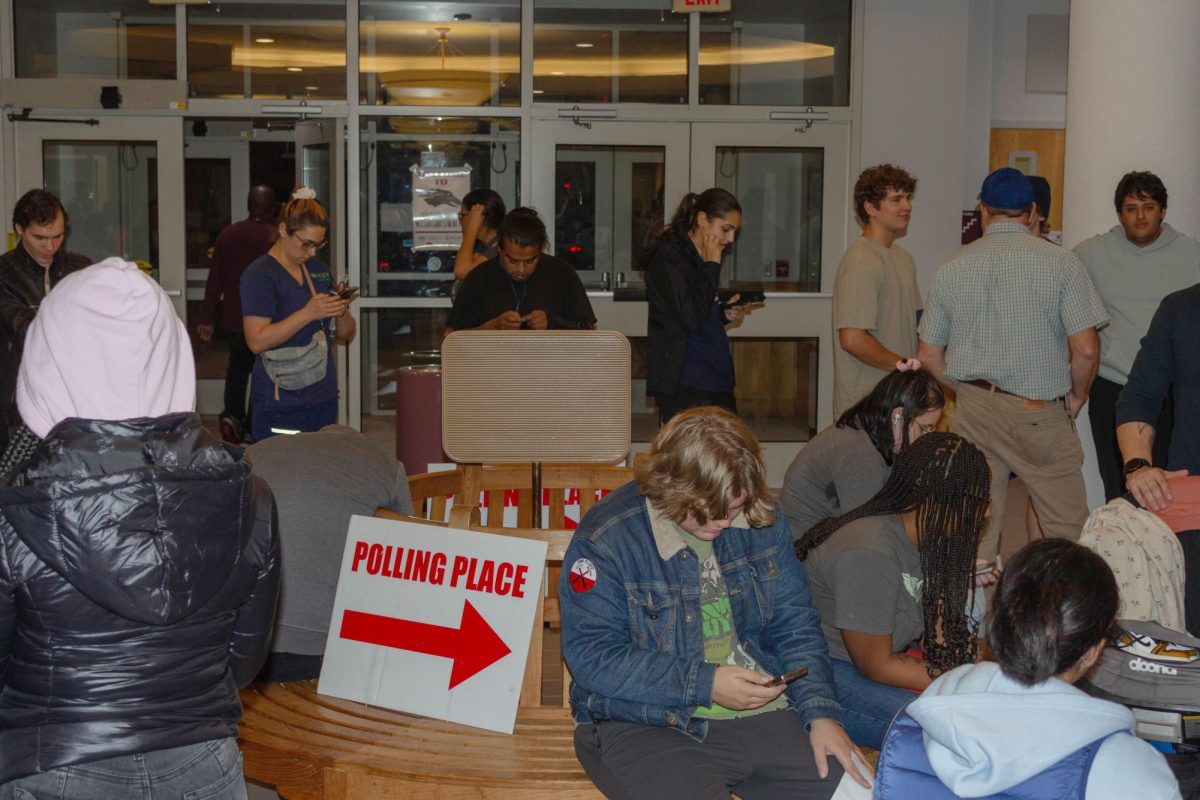 A few people sit and wait to register to vote in the only benched seating area while others have resorted to sitting on the floor Nov. 11, 2024 at the Carbondale Civic Center in Carbondale, Illinois.