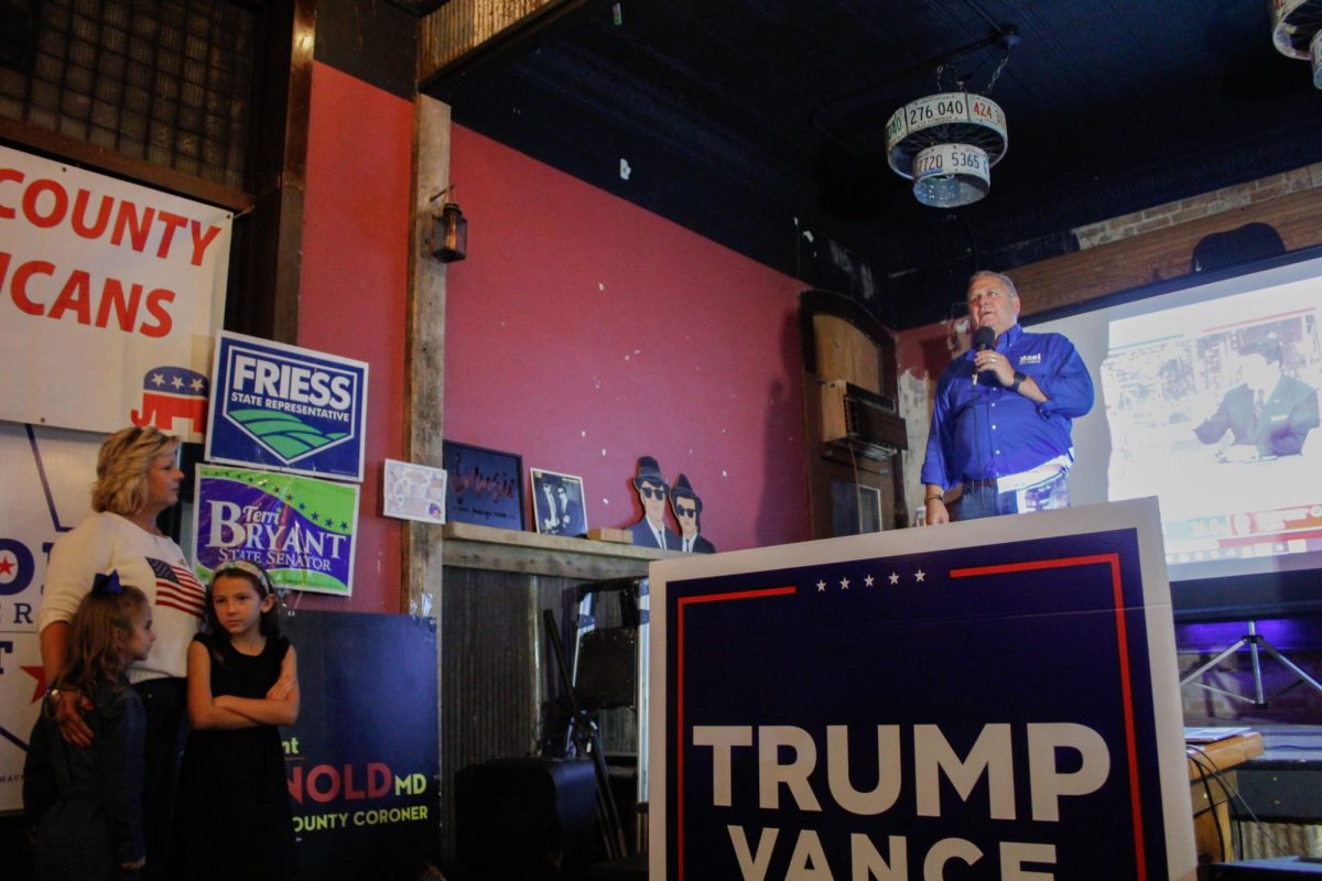 U.S. Rep. Mike Bost gives a speech on stage while his wife Tracy Bost and grandkids watch at Brew Brothers Taproom Nov. 5, 2024 in Murphysboro, Illinois.