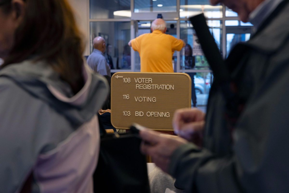 A voter registration sign points to the left as the line wraps around the building Nov. 5, 2024 in Carbondale, Illinois.