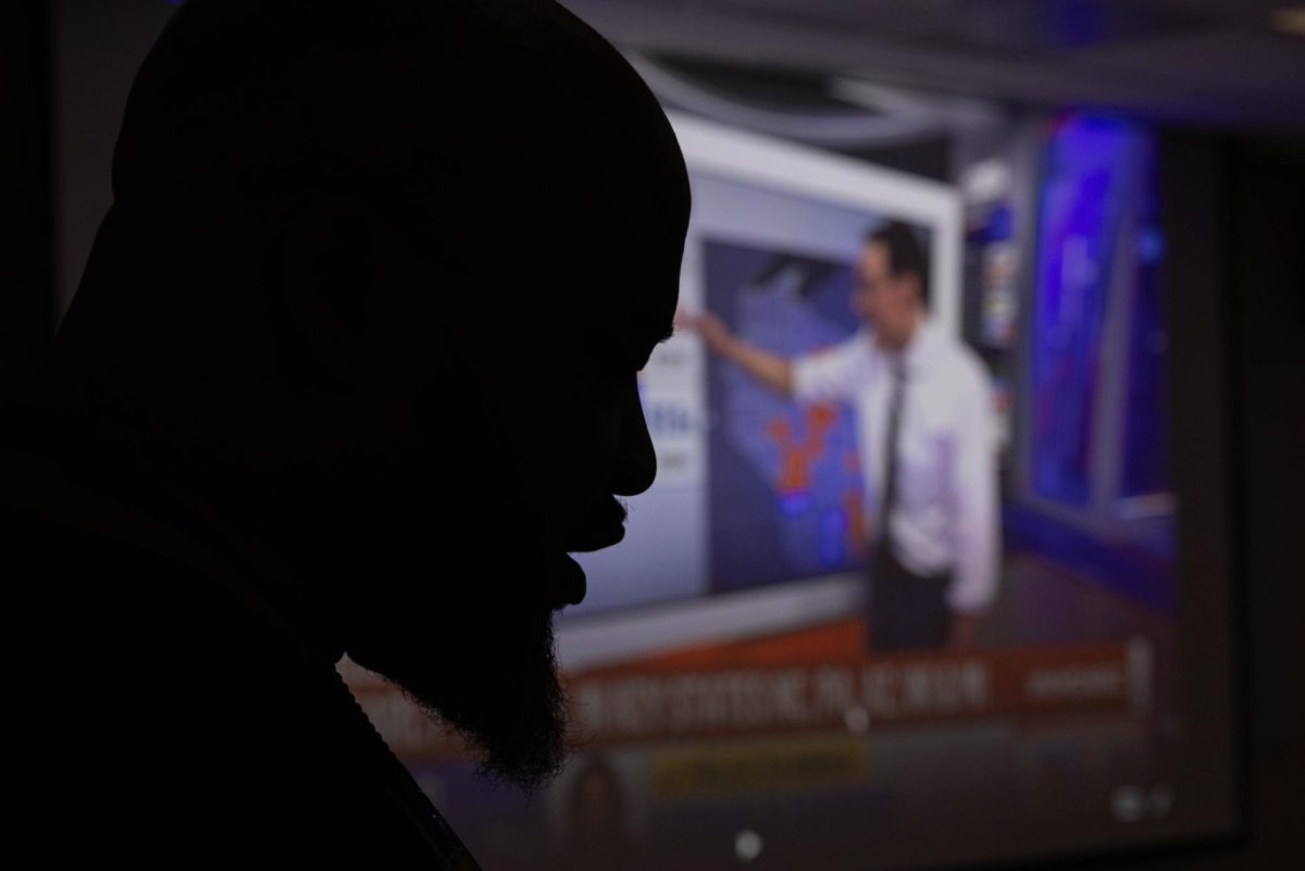 Senior Pastor of Zion Temple Church of God in Christ Stephen Robinson leads a prayer for attendees of an election watch party hosted by the SIU AKA chapter as the live election plays in the background Nov. 5 at Faner Hall in Carbondale, Illinois.