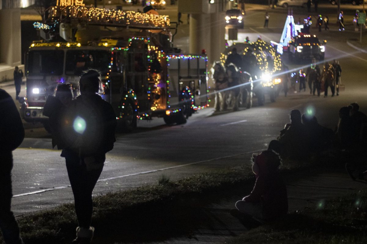 Visitors to the Lights Fantastic Parade walk toward the Carbondale strip and watch the parade from the street Dec. 7, 2024 on Mill street in Carbondale, Illinois.