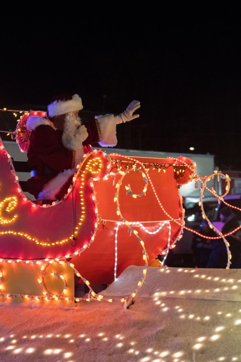 A man in a Santa Claus Costume waves at visitors to the Lights Fantastic Parade Dec. 7, 2024 on the Strip in Carbondale, Illinois.