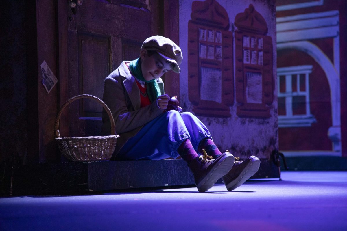 Jack Kincaid, playing a poor boy, cleans an apple he dropped earlier on stageDec. 4, 2024 play at McLeod Theater in Carbondale, Illinois. 