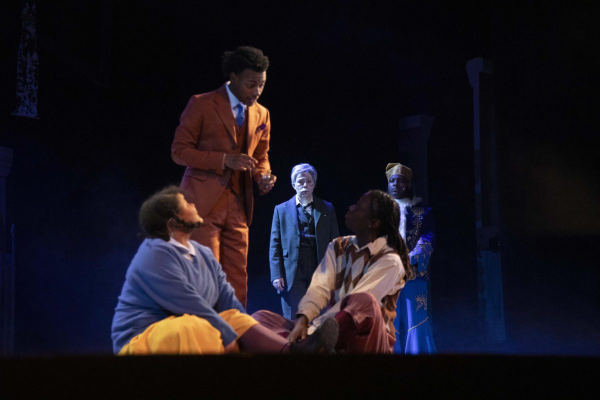 Ebenezer Scrooge (Sawyer Richman) and The Ghost of Christmas Present (Damarion Clark) watch as Belinda (Yasmin Martinez-Powell), Bob (J’kuion West), and Peter Cratchit (Quincy Smith) spend their Christmas eve together Dec. 4, 2024 at McLeod Theater in Carbondale, Illinois. “I really do love it (the Cratchit family scene). It really does show what family is… I think another favorite moment I have is when me and Belinda are arguing in our scene because, you know, I can relate to that. I've done that with my little sister before,” Smith said.