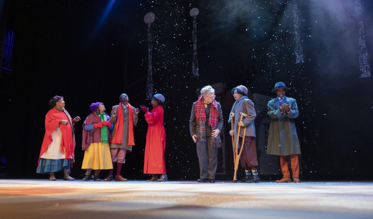 The cast of "A Christmas Carol plays in the falling fake snow as it falls over the stage during one of the final scenes of the play Dec. 4, 2024 at McLeod Theater in Carbondale, Illinois.