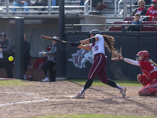 Jackie Lis (00) slams the ball towards left field against Wisconsin at Charlotte West Stadium on Mar. 8, 2025.