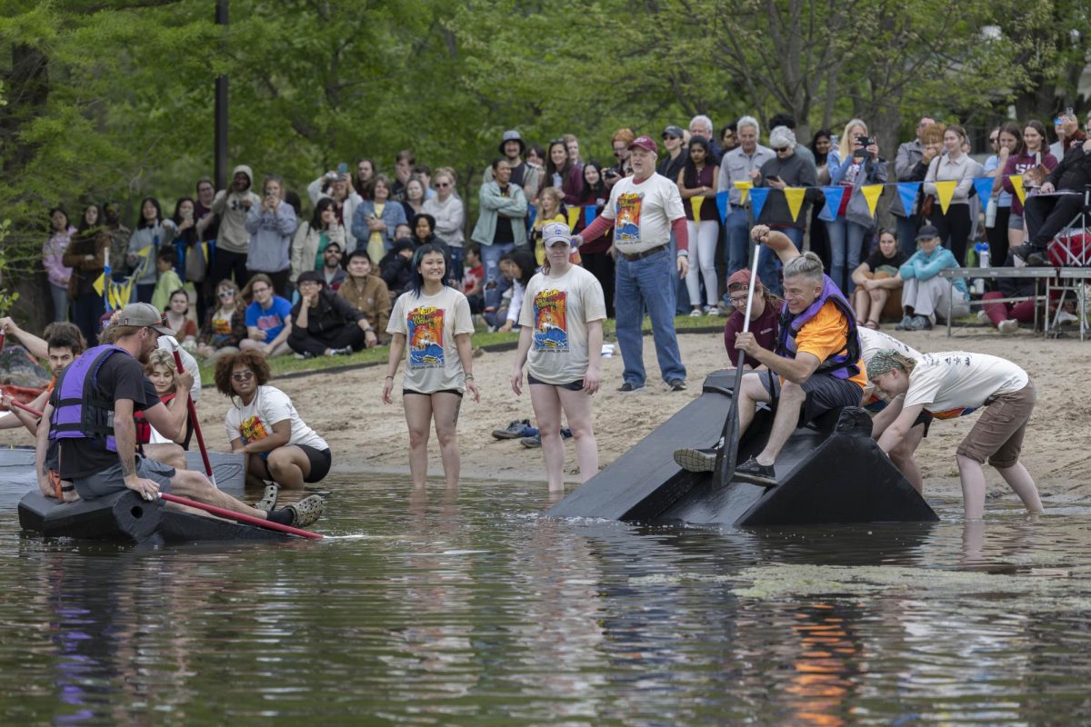The team "Just Boat" sinks immediately while Alpha Kai Sigma volunteers try to push the boat more into the water and look at the boat at the Cardboard Boat Regatta in campus lake April 26, 2025 in Carbondale, Illinois. 