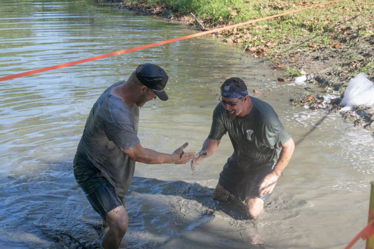 Jake Ryan and Andy Titsworth shake hands while wading through water Sept. 27th, 2025 in Murphysboro, Illinois. Moments before Andy pulled Jake down into the water.