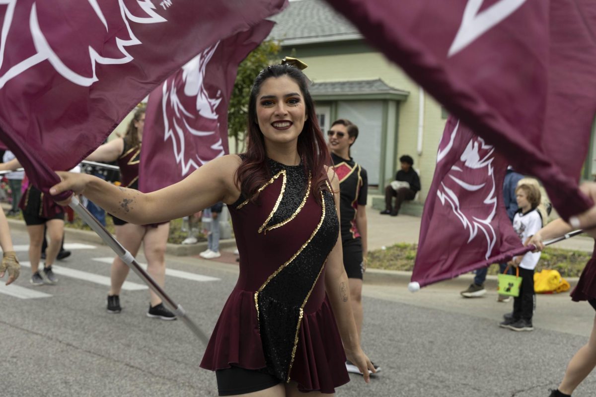 Saluki Silks member Salma Garcia spins her flag to the school song Oct. 25, 2025 at the Homecoming Parade in Carbondale, Illinois. 