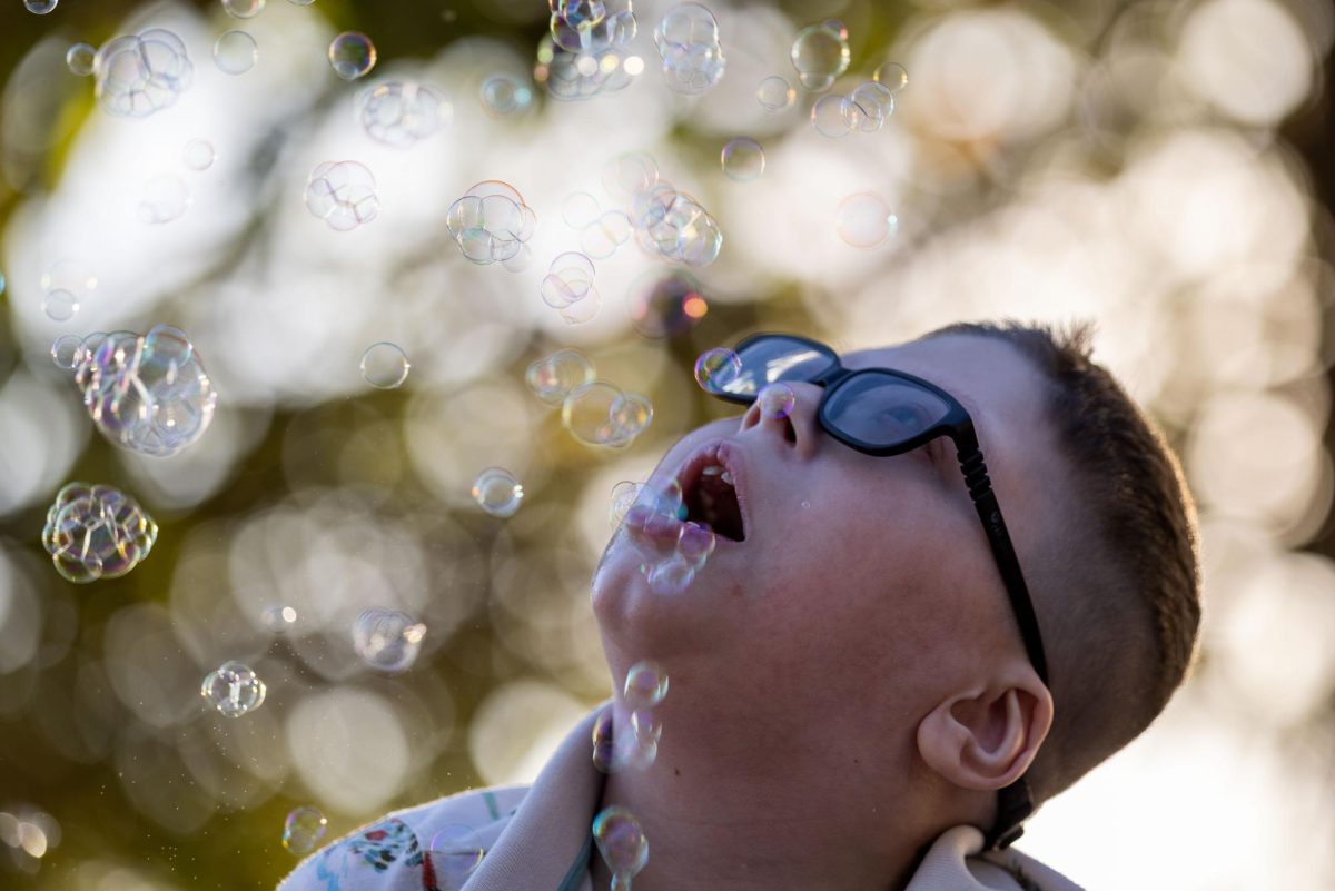 Tobias Edwards, 10, watches as bubbles float around him while he sits in the driveway with his nurse, Bri Rollhaus, and plays with a bubble machine Sept. 25, 2025 in Union, Missouri. 