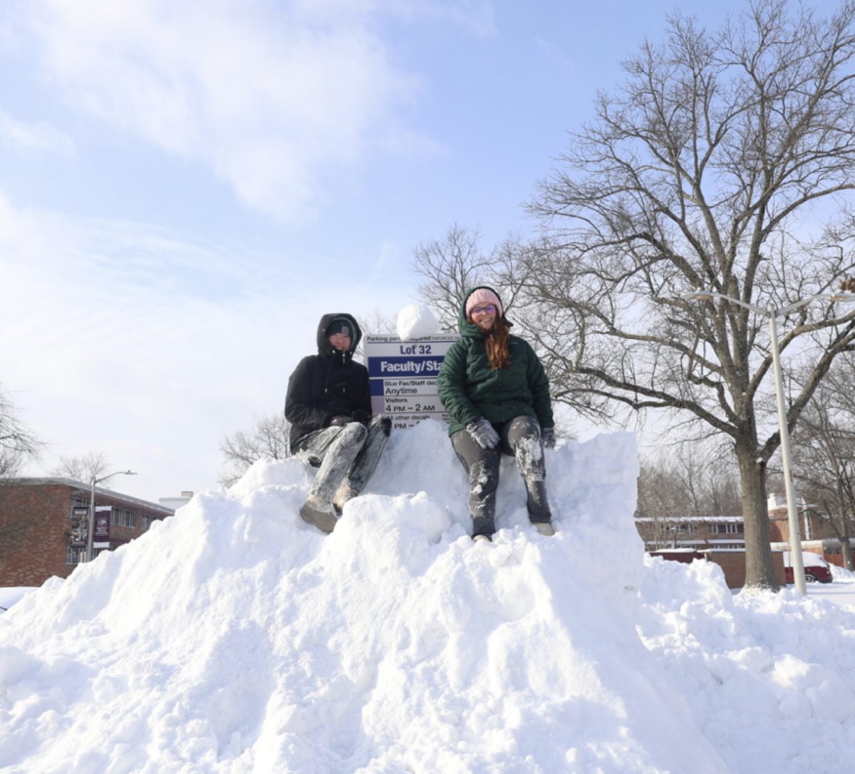 SIU students Ashley Hintz and Summer Negray pose atop a mound of snow in front of the dorms on west campus Jan. 25, 2026 in Carbondale, Illinois.