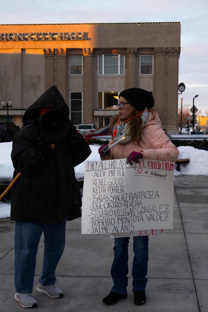 Allison Powell, co-lead of Indivisible Marion, holds a sign with a list of individuals who were killed by ICE while listening to a participant chant Jan. 31, 2026 in Marion, Illinois.
