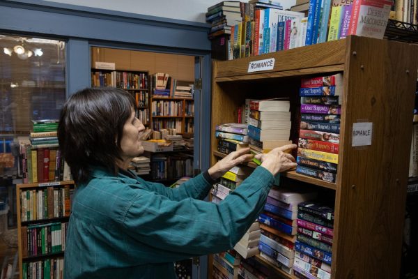 Sarah Heyer adjusts books on the romance shelf Feb. 5, 2026 at Confluence Books in Carbondale, Illinois. Heyer said she is working on restocking the section with newer romances. 