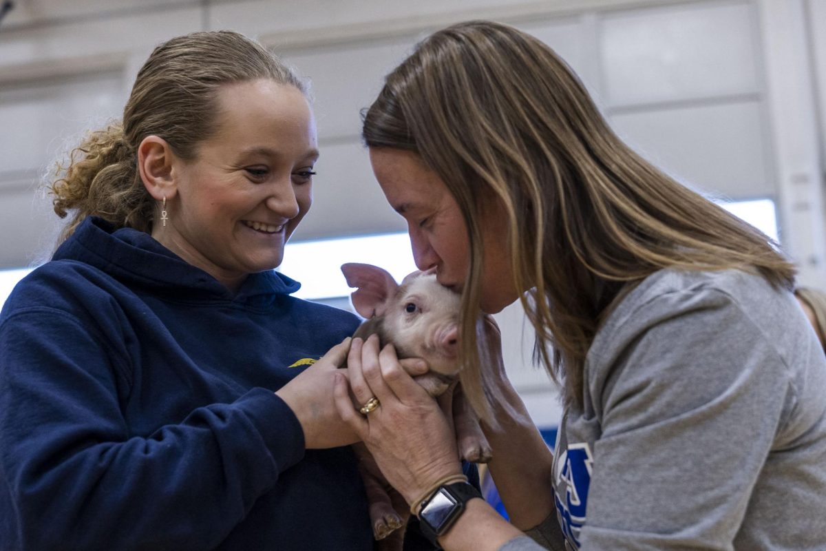 Band teacher Ashley Followell kisses the head of a week-old piglet as its held by senior FFA member Addison Bonner Feb. 27, 2026 at Anna-Jonesboro High School in Anna, Illinois. 