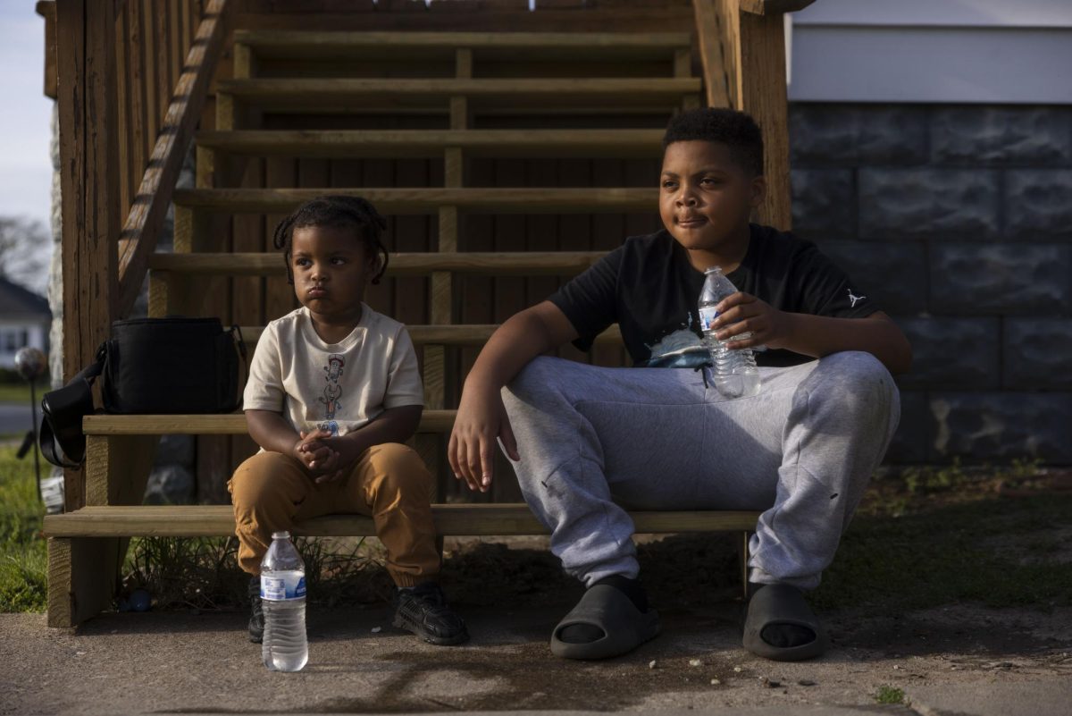 Dax and Chase Hibbler drink water while they sit on a set of stairs as family members play basketball and grill food April 11, 2026 in Murphysboro, Illinois.