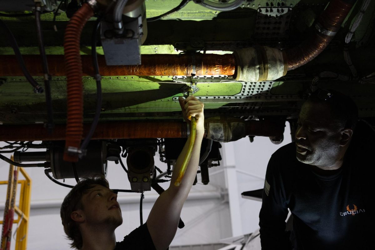 Terry Maddox (right) watches on as Landon (left) installs a new drainage tube before putting on a body fairing on the bottom of the plane April 10, 2026 at the Southern Illinois Airport in Murphysboro, Illinois.