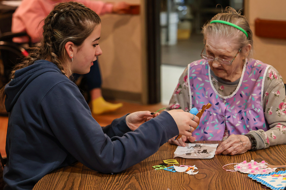 FFA member Olivia Toller helps Mary apply foam stickers to her spring-themed door decorations Sheila (left) uses the help of FFA member Bruce Still to create spring-themed crafts Feb. 24, 2026 in Du Quoin, Illinois.