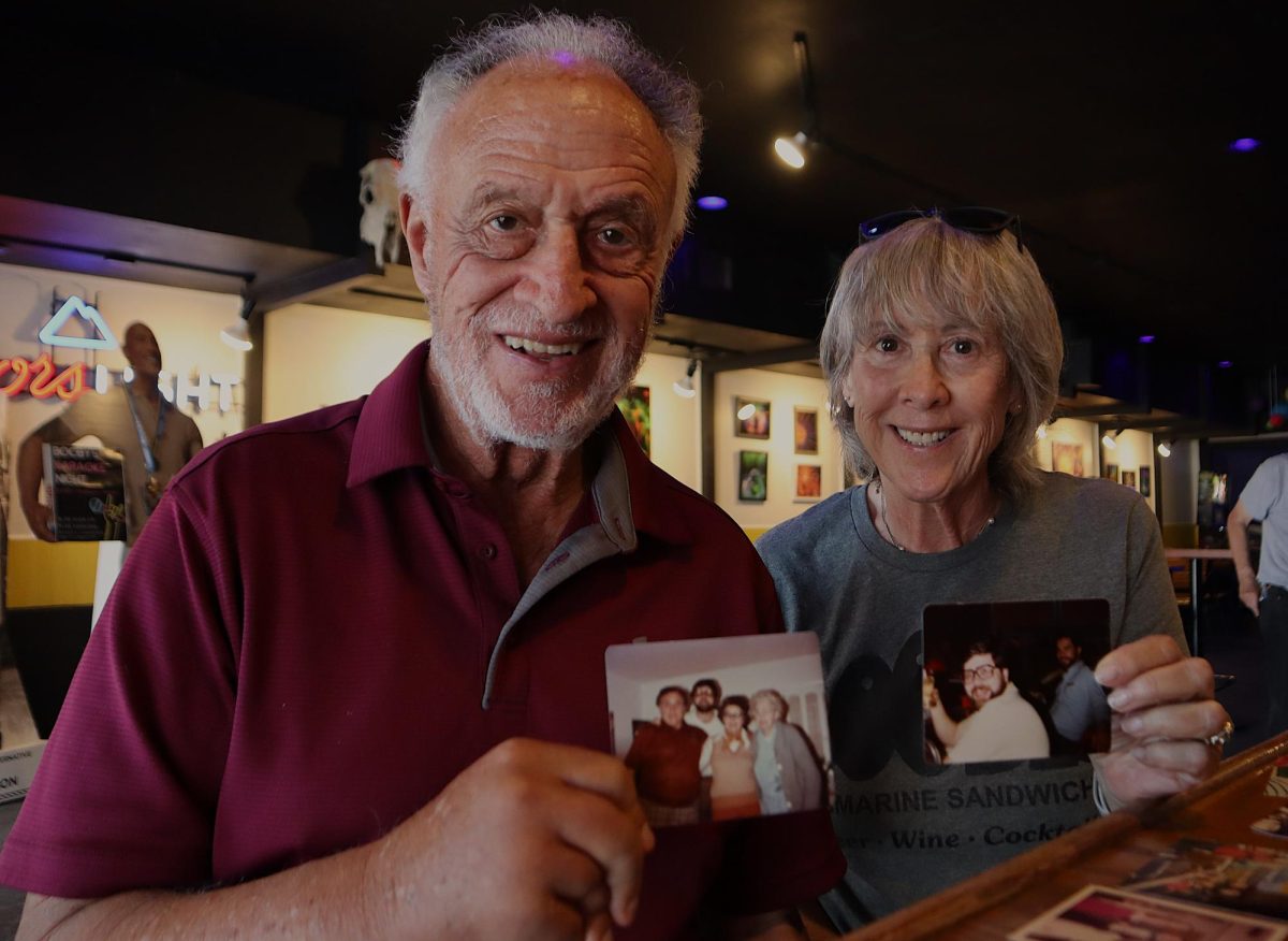 Bruce Levine and Robyn Duenow pose with old photos June 8, 2026 at Booby's Bar and Sandwiches in Carbondale. The two stopped by with a group of friends who had worked together when the business originally opened in the early '70s to reminisce and check out the changes that have taken place over time. 